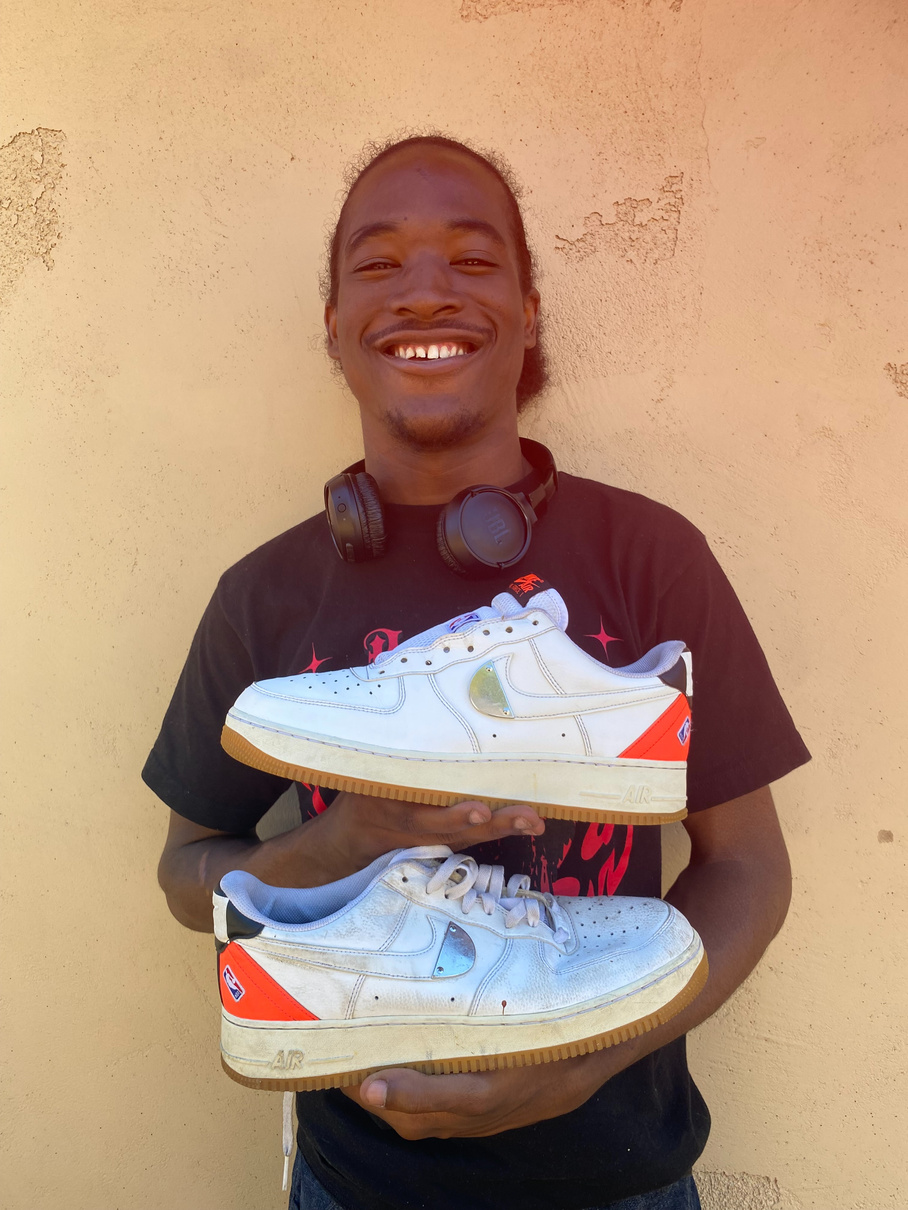 Dontrell holding a pair of white Nike Air Force 1 sneakers