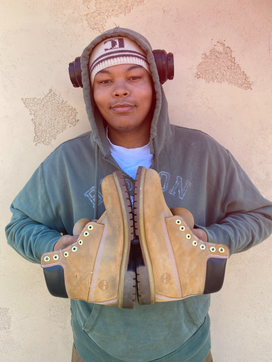 Jayden holding a pair of tan boots